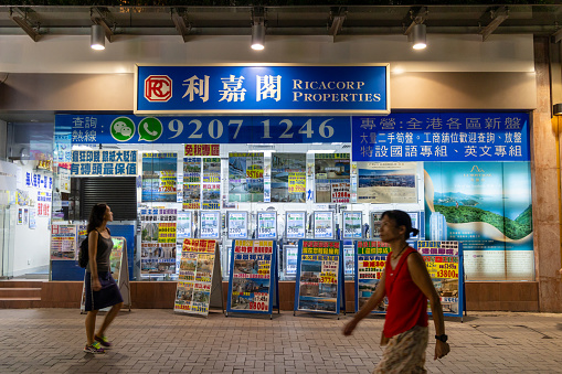 Hong Kong - August 12, 2023 : Pedestrians walk past a property agency store in Whampoa residential district in Hung Hom, Kowloon, Hong Kong.