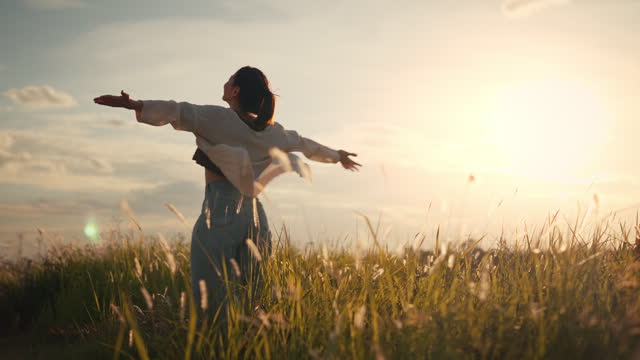 Happy smiling young woman enjoying nature. Young asian woman having fun in the meadow. freedom concept. Sunset