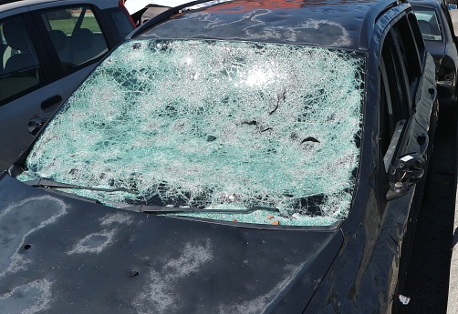 Windshield and bodywork of a car severely damaged by hailstorm.