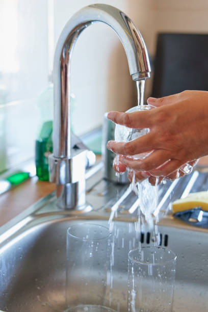 istock Woman washing glass cup with sponge and detergent in kitchen 1609841494