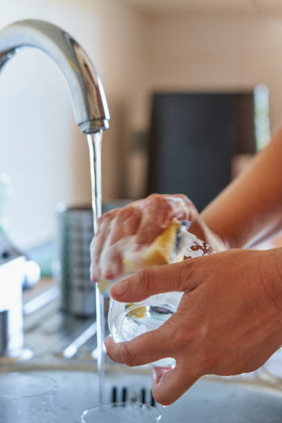 istock Woman washing glass cup with sponge and detergent in kitchen 1609841837