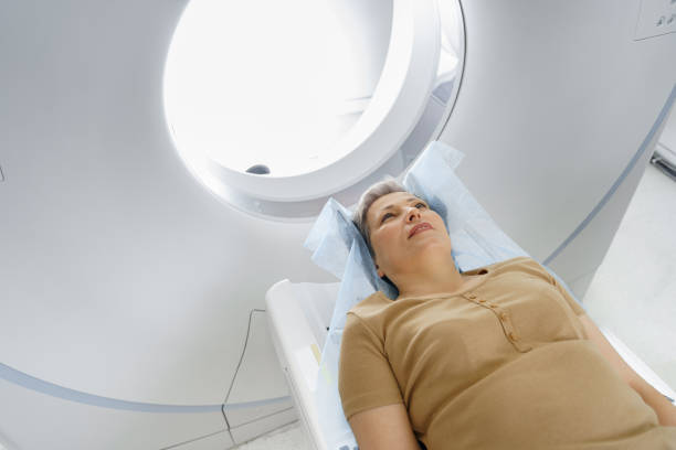 Female patient lying on table and entering CT machine during examination procedure in hospital Patient entering CT machine during examination procedure in hospital. High quality photo x ray image medical occupation technician nurse stock pictures, royalty-free photos & images