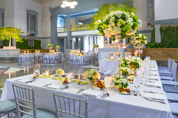 Wedding Event Decorations Tables with Decorations, Bouquets of Flowers, Food, Candles and Fine Decorations are Ready for Wedding or Big Venue inside a huge Ballroom or Wedding Reception ballroom photos stock pictures, royalty-free photos & images