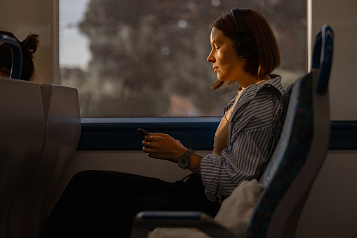 Smiling woman listen music in headphones while traveling in public transport . High quality photo