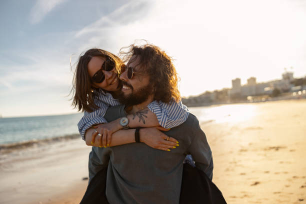 istock Handsome couple in love hugging while walking along the beach on sunny day 1609859879