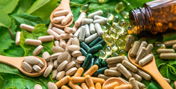 istock Capsules herb supplements on green leaves background. Selective focus. 1609865200