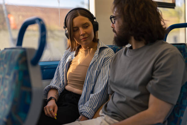 istock Young lovely tourist couple looking each other while riding in public bus 1609865976
