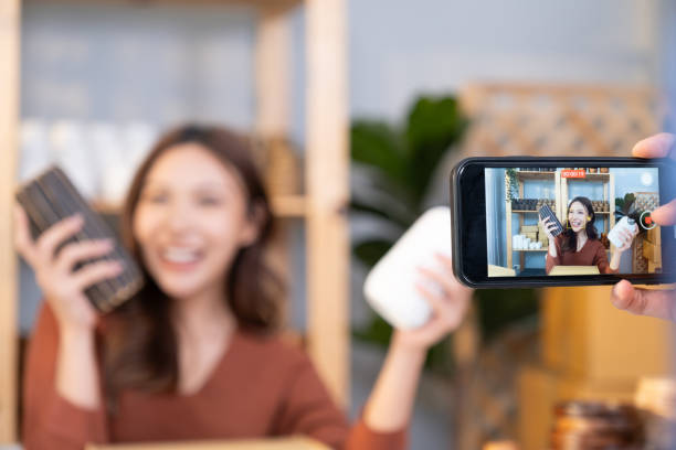 istock Selective focus at smartphone, Young Asian female entrepreneur smile while talking on the phone and check customer order from online shopping inside of home office. New small business start up trend. 1609869764