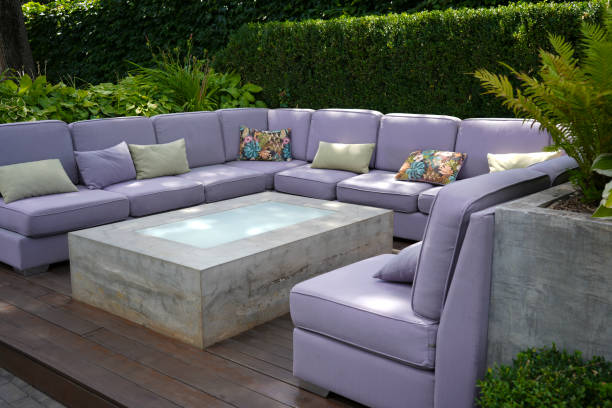 A large lilac sofa and a rectangular glass table in an outdoor cafe. Modern style.
