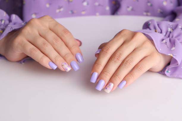 istock Female hands with purple manicure nails 1609914336