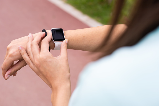 Female athlete checking a smartwatch tracker for running outdoors. Sport, exercise and active lifestyle.
