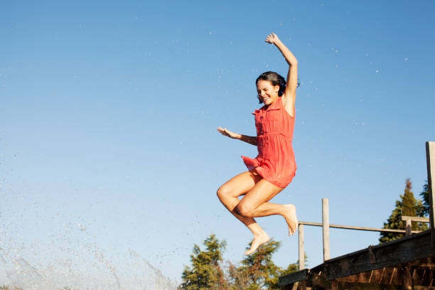 Young girl jumping into a swimming pool on a clear, sunny summer day