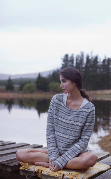 istock Pensive woman sitting on dock at lake 160992339