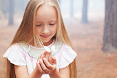 istock Close up of girl holding butterfly in woods 160992457