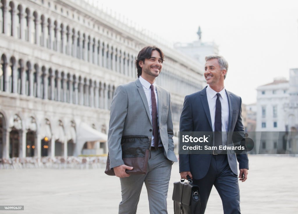 Smiling businessmen walking across St. Mark's Square in Venice  Businessman Stock Photo