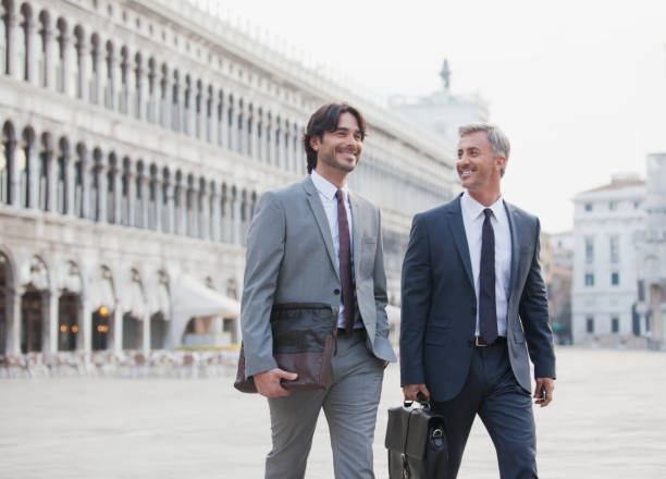 sorrindo homens de negócios cruzando praça de são marcos, em veneza - men briefcase business bag - fotografias e filmes do acervo