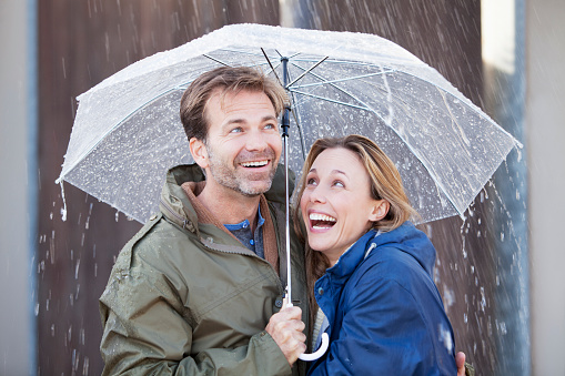 Happy couple under umbrella in downpour