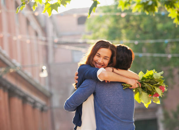 istock Smiling woman with flowers hugging man 160992771