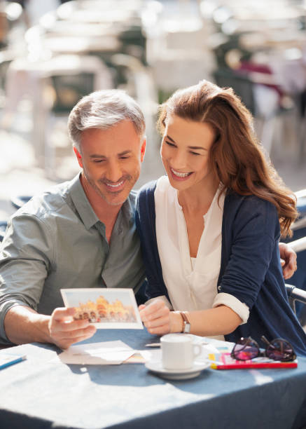 coppia sorridente guardando una cartolina al caffè all'aperto - coffee couple italy drinking foto e immagini stock