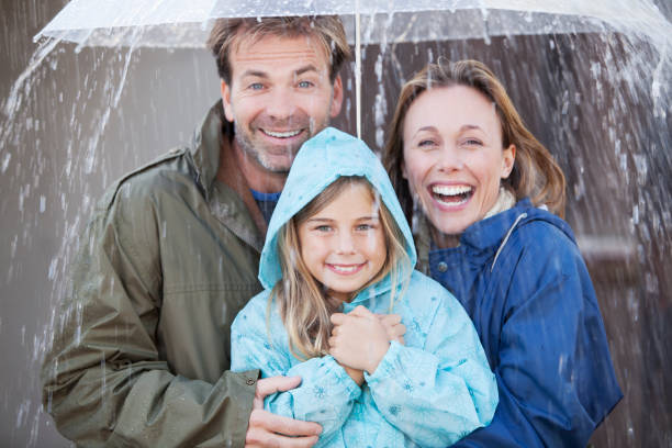 retrato de família entusiasmada sob guarda-chuva em altura - blurred motion clothing mother offspring - fotografias e filmes do acervo