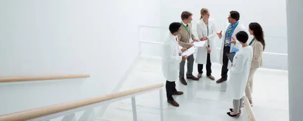 Photo of Business people and doctors meeting on landing of stairs