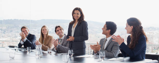 co-workers clapping for businesswoman in conference room - leidinggevende stockfoto's en -beelden