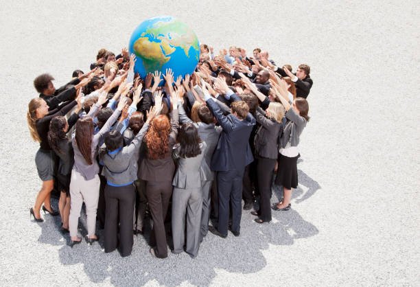 Crowd of business people in huddle reaching for globe  arms raised women business full length stock pictures, royalty-free photos & images