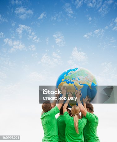istock Team in green t-shirts lifting globe overhead 160993291