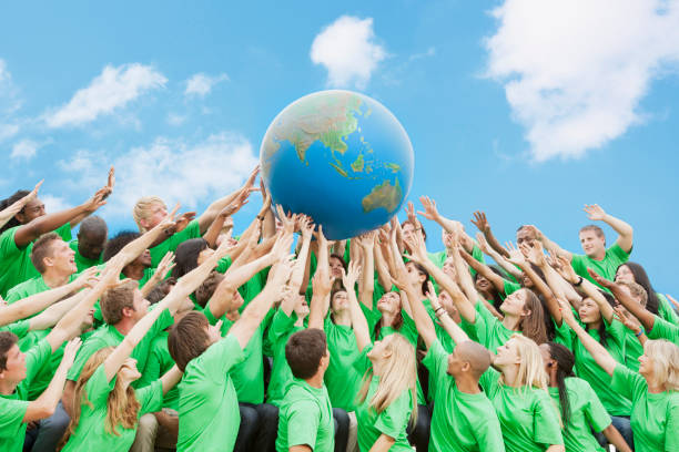 équipe de green globe t-shirts en levant au-dessus de la tête - responsibility challenge globe earth photos et images de collection