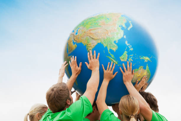 istock Team in green t-shirts lifting globe overhead 160993308