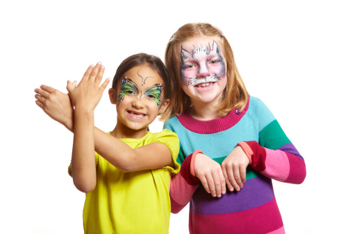 Young girls with face painting of cat and butterfly smiling on white background