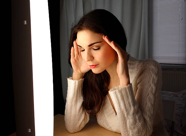 Medicative effect of sun- and daylight A young woman relaxing by using light therapy. Light therapy is very useful especially in winter because of winter depression, lack of sunlight and listlessness. light therapy stock pictures, royalty-free photos & images