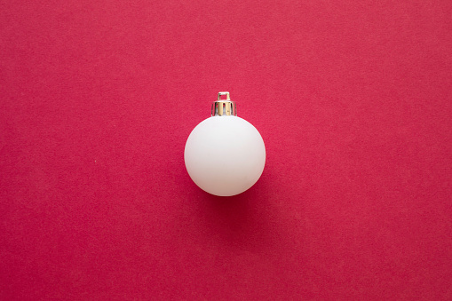White Christmas ball on red background.