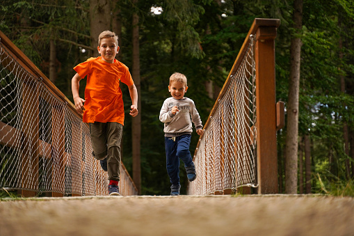 Children race across a wooden bridge in the park. Little athletes