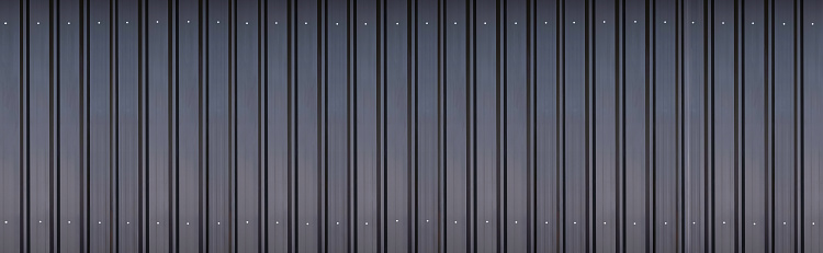 Panoramic view of black aluminium corrugated steel wall background with gradient light on surface