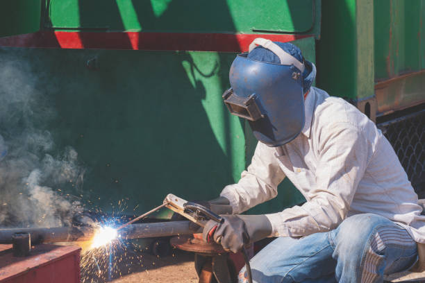istock Welder with safety equipment using arc welding machine to welding galvanized steel pipe in construction site area 1609986433