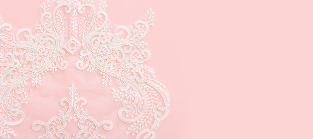 white delicate lace fabric over pink background