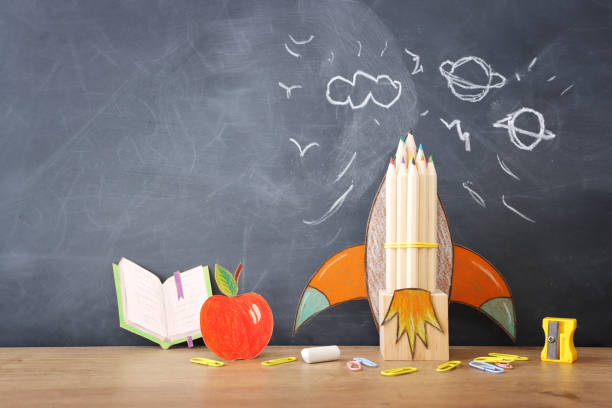 istock Back to school concept. rocket and pencils over classroom blackboard. Top view 1609991227