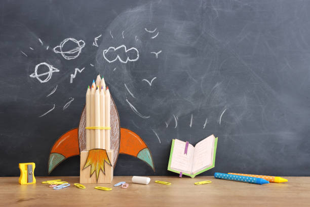 istock Back to school concept. rocket and pencils over classroom blackboard. Top view 1609991229
