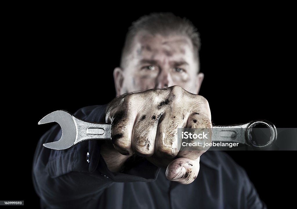 Mechanic holding wrench A mechanic covered in grime and grease holds out a box wrench during repairs. Mechanic Stock Photo