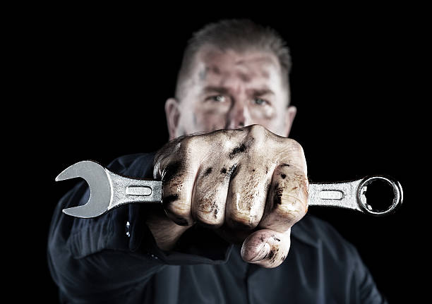 Mechanic holding wrench A mechanic covered in grime and grease holds out a box wrench during repairs. dirty hands stock pictures, royalty-free photos & images