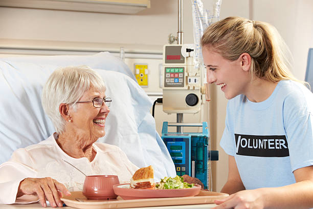 adolescente senior paciente de sexo femenino de voluntarios que sirve una comida - care community 80 plus years cheerful fotografías e imágenes de stock
