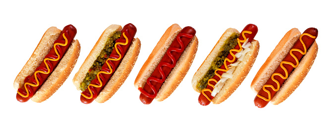 Assortment of unique hot dogs with a variety of toppings in sesame seed buns. Above view isolated on a white background.