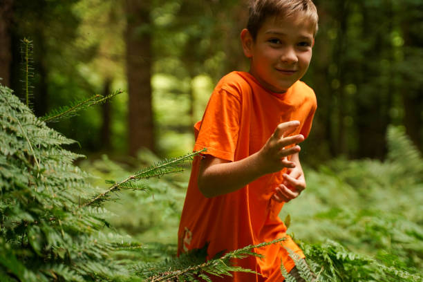 istock A cheerful boy sneaks through a dense forest. Hide and seek in the forest. Have a fun vacation. Outdoor activities. 1610033341