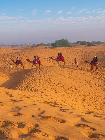 Jaisalmer, India - December 24, 2022:  Tourists enjoying camel desert  safari with beautiful sky at Golden city of India.   Sam Sand Dunes.