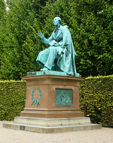 Copenhagen King's Garden (Kongens Have) public park:lateral view of  bronze monument to Hans Christian Andersen with a book in hand, by August V. Saabye in 1880