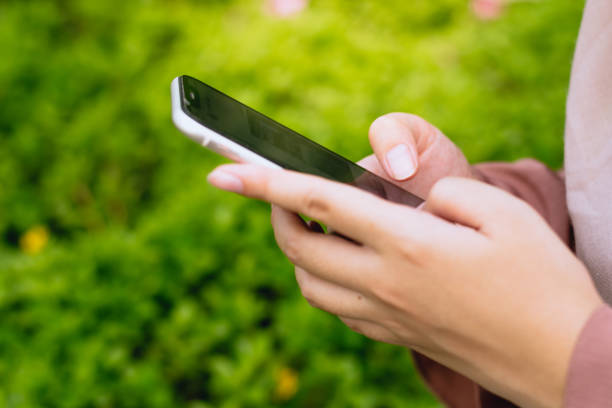 istock Asian woman using smartphone with a green plant background 1610081799