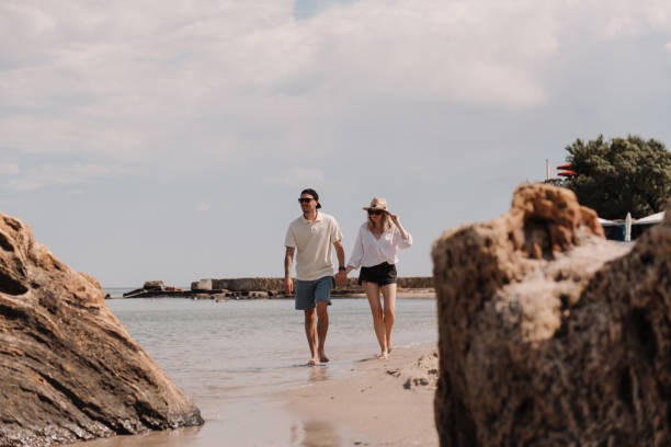 istock Beautiful young couple holding hands while walking by the beach together 1610164903