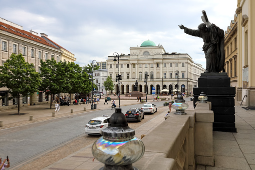 Warsaw, Poland - July 19, 2023: Staszic Palace in the city center at Nowy Swiat Street. Other buildings and a sculpture of Christ with a cross in front of the church are visible