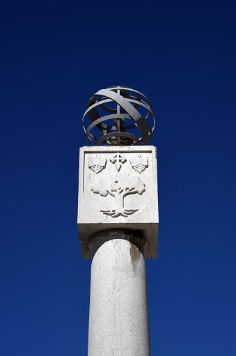 Moita, Setubal district, Portugal: stone column with armillary sphere and the municipal coat of arms - Moita's emblem displays a cork oak and Cross of Santiago (St James) accompanied by two bunches of grapes. Known as 'Coluna Padrão', occupying the center of Praça da República square, presumably in the place of the former pillory.